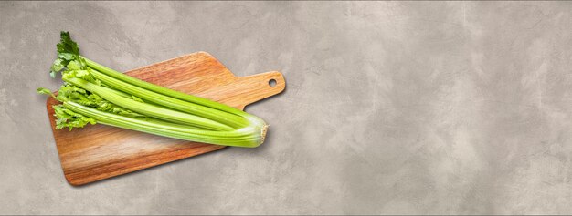 Celery branch bunch on a wooden cutting board. Isolated on concrete banner background