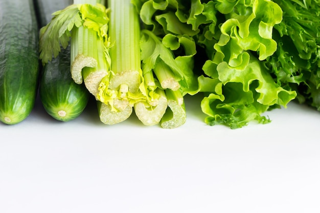Celery, lettuce and cucumbers isolated on a white wall