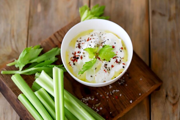 Celery sticks with white sauce in a bowl Healthy food