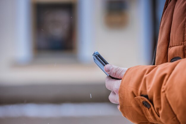 冬の街の中で男性の手に携帯電話