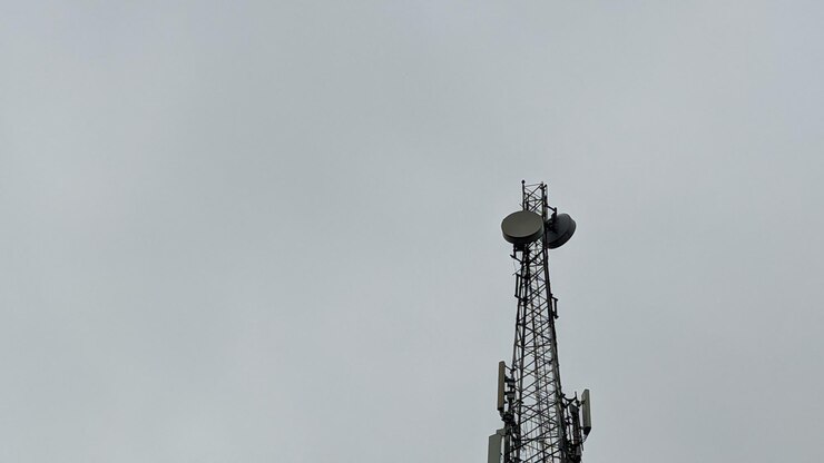 Photo a cell tower with a large antenna on top of it.