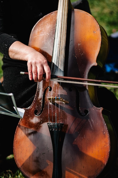 Cellist speler handen Violoncellist cello spelen op achtergrond van veld Muzikale kunst concept passie in muziek Klassieke muziek professionele cello speler solo optreden Onherkenbaar persoon