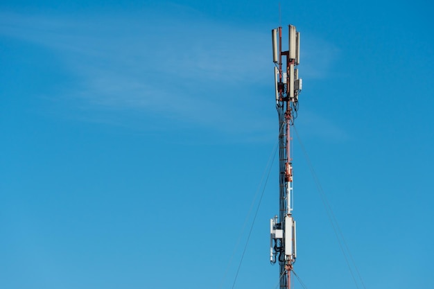 A cellular communication antenna installed on the roof of a\
highrise building against a blue sky background 5g radio network\
telecommunication equipment with radio modules and smart\
antennas