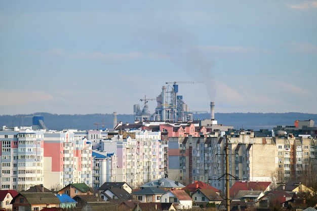 Cement plant with high factory structure and tower cranes at industrial production area near city urban area Manufacture and global industry concept