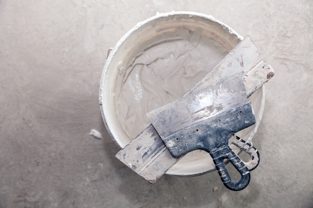 Cement plaster and trowels in construction bucket