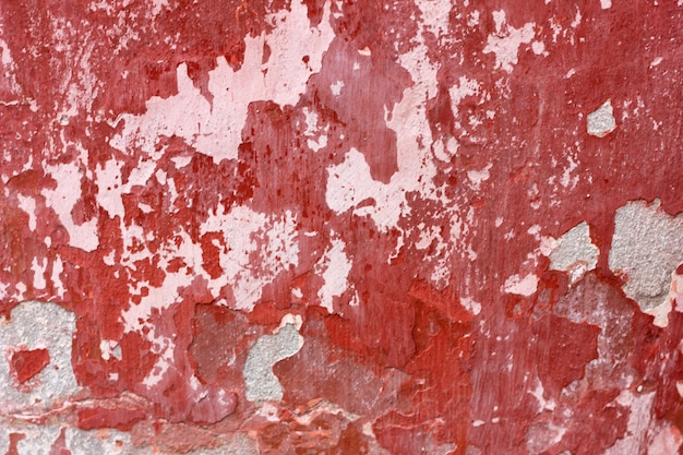 cement wall with red paint, rough background. Abstract concrete background with old peeling red paint.