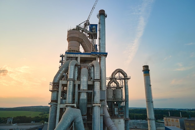 Cementfabriek met hoge fabrieksstructuur en torenkranen in het industriële productiegebied Vervaardiging en wereldwijd industrieconcept