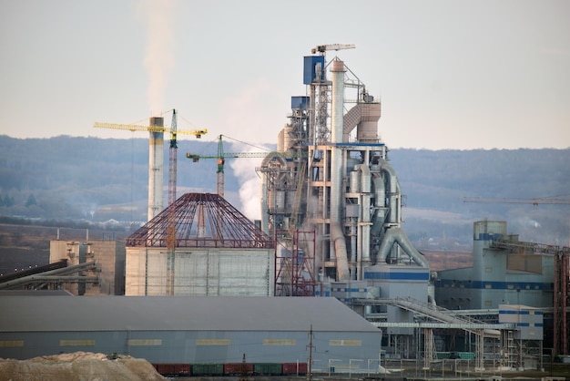 Cementfabriek met hoge fabrieksstructuur en torenkranen op industrieel productiegebied Fabricage en wereldwijd industrieconcept