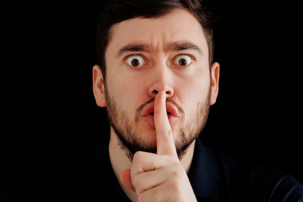 Censorship concept secret information mysterious bearded man looking at camera and putting finger on