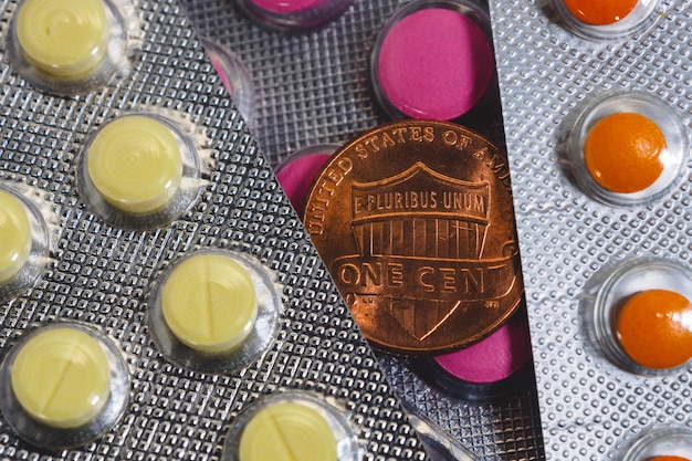 Cent coin among blisters of colorful pills