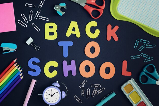 Al centro di uno sfondo nero con lettere colorate allineate iscrizione ritorno a scuola.