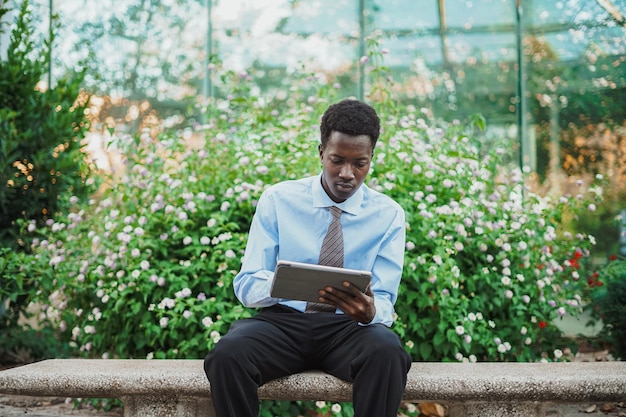 Centered shot of african businessman using a tablet computer while he is sitting on a bench