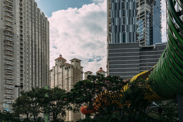 Центральный Джакарта городской пейзаж с высотного здания, небоскребы и отель в туристической зоне с зелеными деревьями.