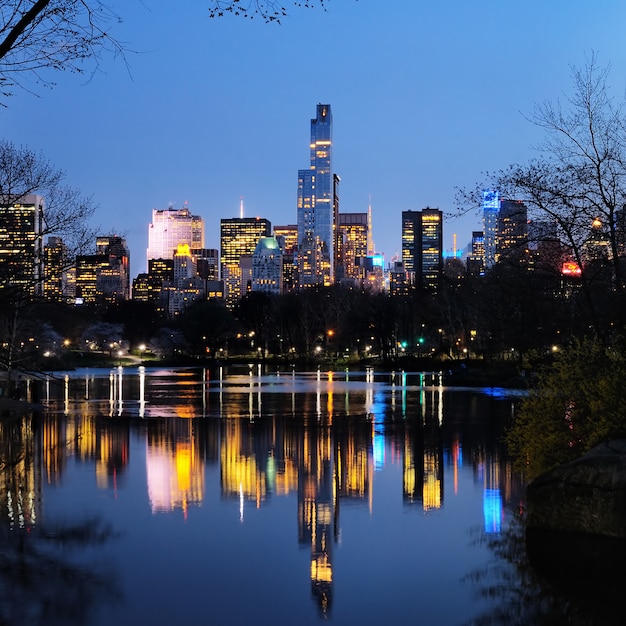 Photo central park in dusk and buildings reflection in midtown manhattan new york city