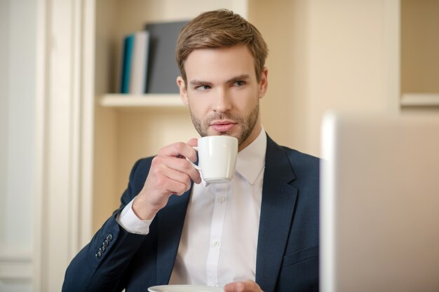 A CEO drinking coffee while working with a computer