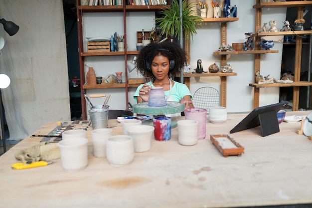 Ceramic artist painting exterior surface of pottery piece