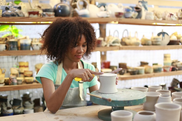 Ceramic artist painting exterior surface of pottery piece