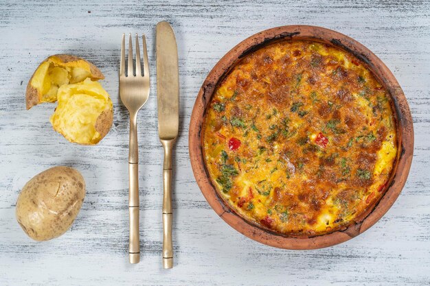 野菜のフリッタータとシンプルなベジタリアン料理のセラミックボウルトマトペッパーオニオンとチーズのフリッタータを木製のテーブルにクローズアップイタリアンエッグオムレツ