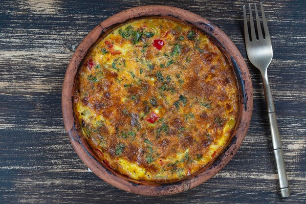 Ceramic bowl with vegetable frittata simple vegetarian food Frittata with tomato pepper onion and cheese on wooden table close up Italian egg omelette