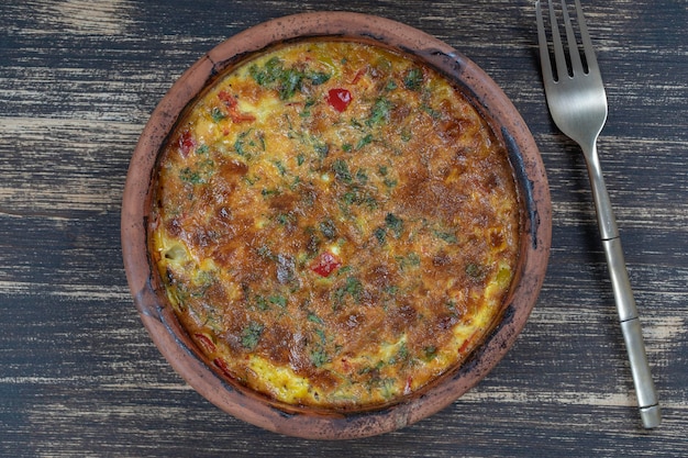 Ceramic bowl with vegetable frittata simple vegetarian food Frittata with tomato pepper onion and cheese on wooden table close up Italian egg omelette