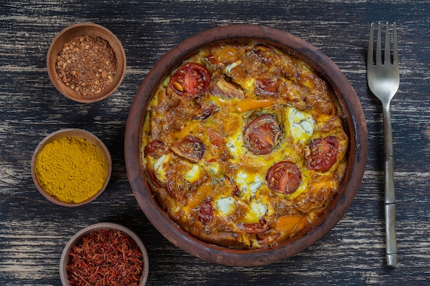 Photo ceramic bowl with vegetable frittata, simple vegetarian food. frittata with tomato, pepper, onion and feta cheese on wooden table, close up. italian egg omelette, top view