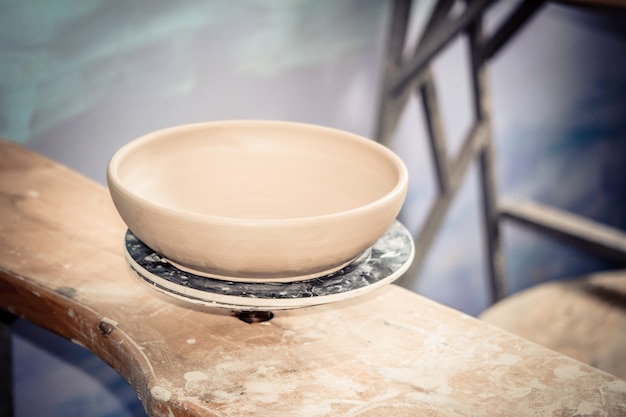 Ceramic clay products stand on the shelf close-up. Sculptor sculpts pots products from white clay. Dark. Workshop pottery. Master crock. Cultural traditions. Handmade. Craft. Twisted potter's wheel.