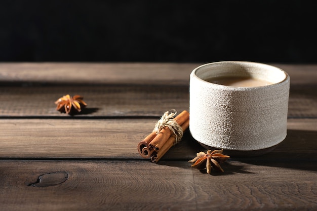 Ceramic cup of masala tea with spice on a wooden table