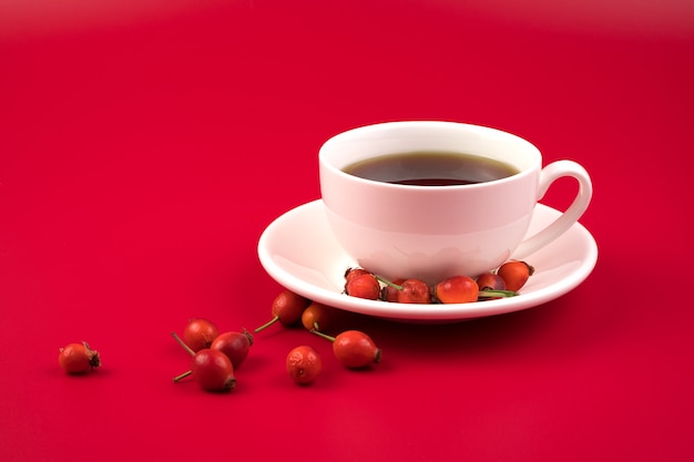 Ceramic cup with hot coffee and rose hips