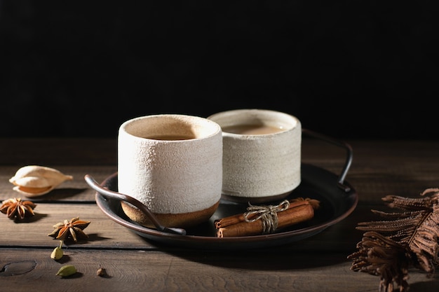 Ceramic cups of masala tea with spice on a wooden table