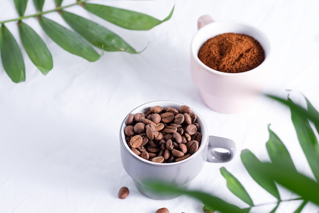 Ceramic cups with freshly roasted coffee beans and fresh ground aromatic coffee