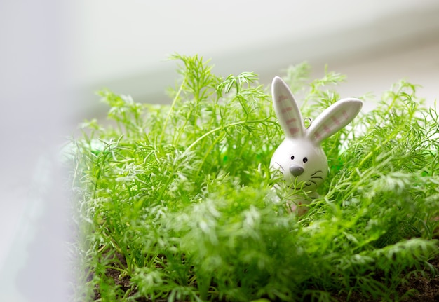 ceramic easter bunny among the green grass on the window