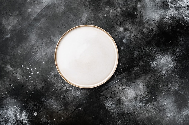 Ceramic empty white plate set with copy space for text or food with copy space for text or food, top view flat lay, on black dark stone table background