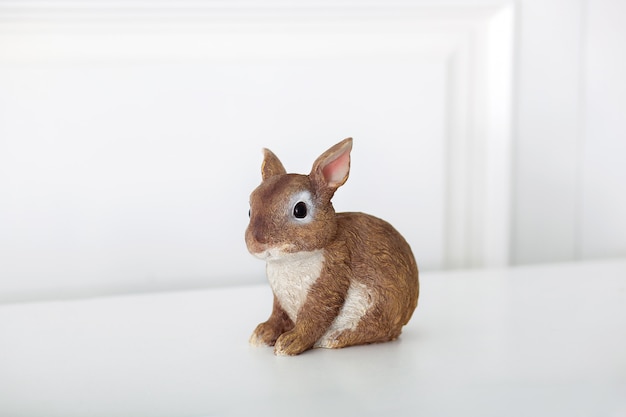 Ceramic figurine of rabbit, Isolated on white wall. Close-up of brown statuette of an Easter bunny. Porcelain bunnie. Easter decoration - ceramic easter rabbit on white surface. Ceramic bunny