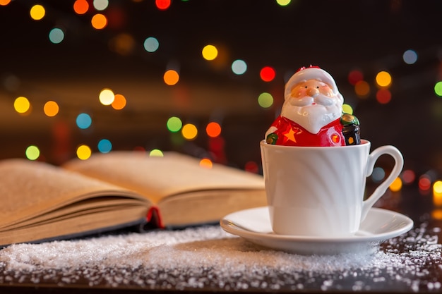 A ceramic figurine of Santa Claus sits in a white cup.