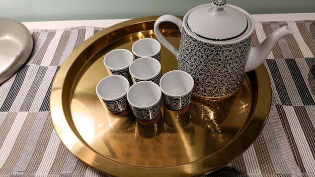 Ceramic glass and ceramic teapot on a brass tray