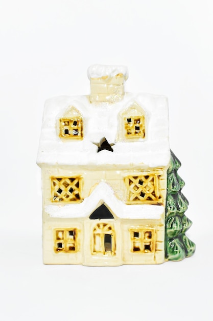 Ceramic house with Christmas tree on white background vintage toy house with snow covered roof