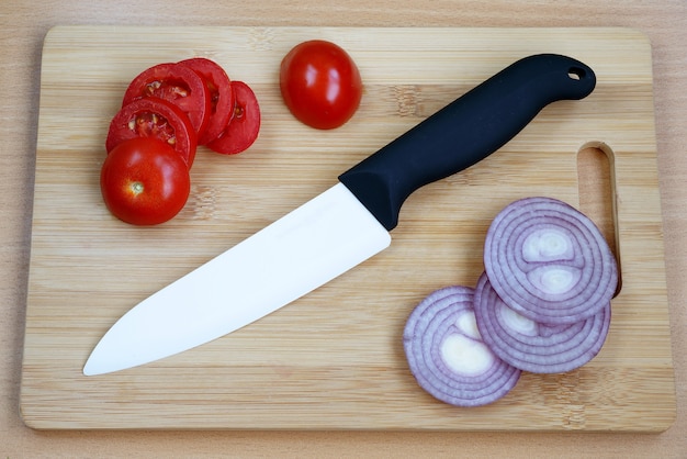 Ceramic knive with black handle on a wooden chopping board