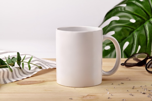 Photo ceramic mug on wooden desktop next to striped tablecloth