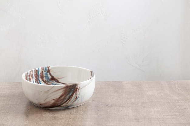 Ceramic multicolored bowl close up on wooden table