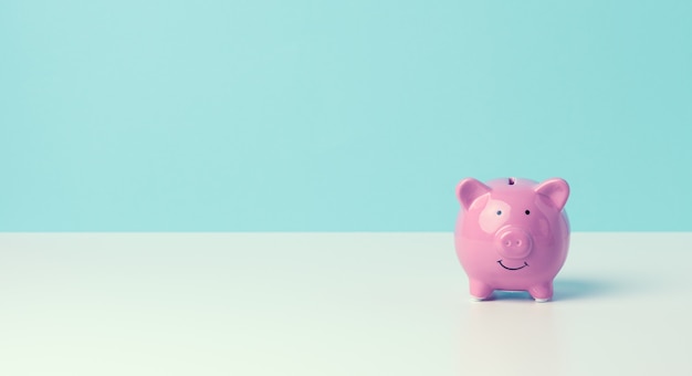 Ceramic pink piggy bank on a blue background. Concept of increasing income from bank accounts, savings, copy space