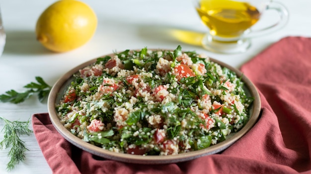 Foto piatto in ceramica di insalata araba tabbouleh su sfondo bianco con tessuti rossi