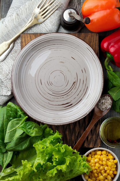 Ceramic plate and ingredients lettuce, spinach, corn, olive oil, Bulgarian pepper, condiments