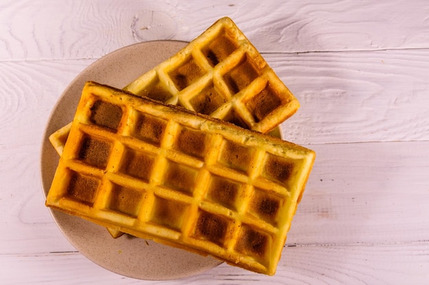 Ceramic plate with belgian waffles on wooden table Top view