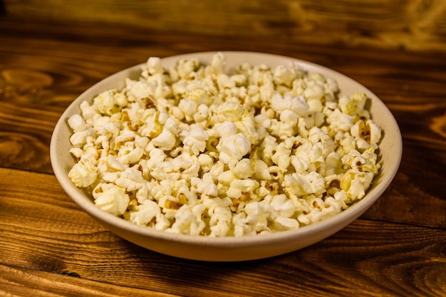 Ceramic plate with popcorn on wooden table