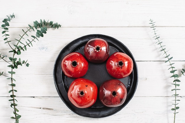 Ceramic plate with red pomegranates on wooden