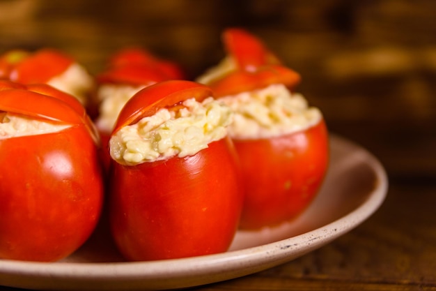 Ceramic plate with stuffed tomatoes on rustic wooden table