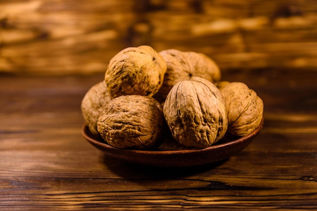 Ceramic plate with walnuts on rustic wooden table