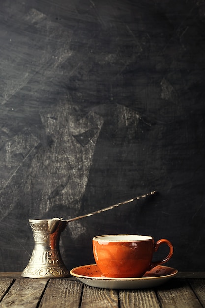 Ceramic small cup of coffee and old coffee pot over black with copy space.