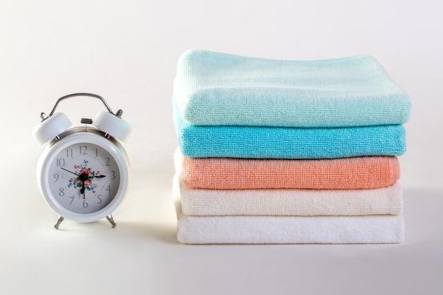 Ceramic soap, shampoo bottles and white cotton towels on white background.