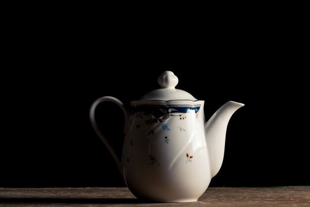 Ceramic Tea pot on the table, Black background.